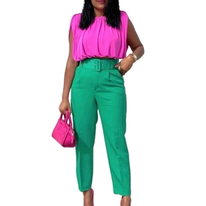 Detail of high-waisted green dress pants with matching belt and fuchsia top