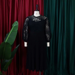 Detailed view of intricate lace cutout pattern and pleated texture on black dress