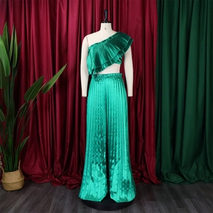 Close-up of emerald green satin pleated two-piece set with ruffled one-shoulder top