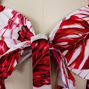 Détail d'un haut à imprimé feuilles tropicales rouge et blanc avec nœud et col en V