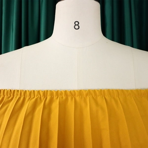 Detail of ginger yellow off-shoulder pleated dress with elastic neckline on mannequin