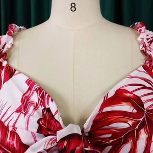 Détail du haut à imprimé feuilles tropicales rouges avec décolleté en V et nœud frontal