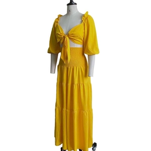 Detail of yellow two-piece summer set showing lace-up crop top and tiered maxi skirt