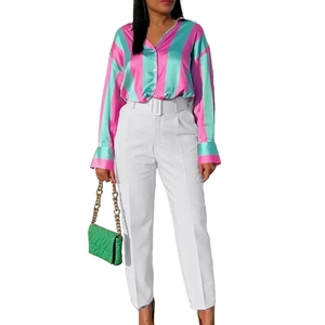 Women stripe satin shirt with white high waist belted trousers and green chain bag