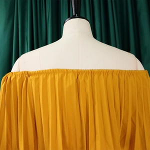 Detailed view of yellow off-the-shoulder pleated top with elastic neckline and draping