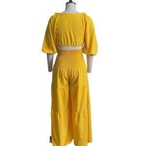 Rear view of yellow two-piece set featuring smocked high waist pants and puff sleeve crop top
