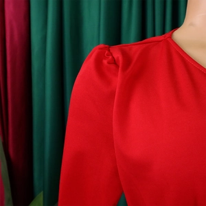Detail of red dress showing puffed shoulder sleeve and textured pleated mesh fabric
