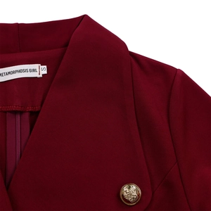Détail de robe bordeaux avec grand revers et bouton métallique doré à blason gaufré