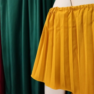 Detail of bright yellow pleated mini dress with elastic waist and fine pleats