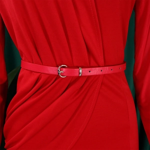 Close-up of a red leather waist belt with a silver circular metal buckle on a pleated dress