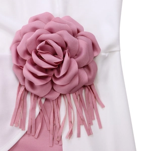 Detail of white dress featuring a large pink 3D fabric flower and elegant hanging tassels