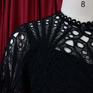 Detail of black hollow lace dress showing intricate mesh patterns and shoulder design