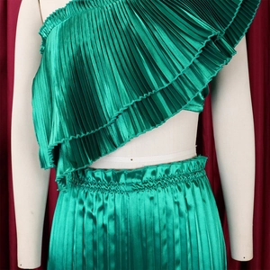 Detailed view of emerald green pleated two-piece set featuring a ruffled one-shoulder top