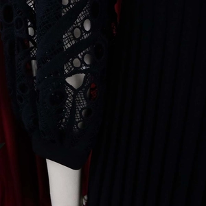 Detail of elegant black dress with hollow lace sleeves and pleated fabric texture