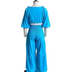 Detail view of bright blue puff sleeve top and tiered wide leg pants with smocked waist