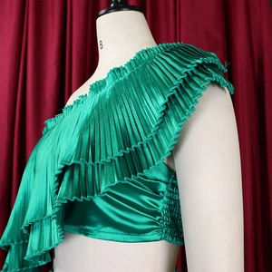 Detail of emerald green satin one-shoulder pleated top with multi-layer ruffles and side gathers
