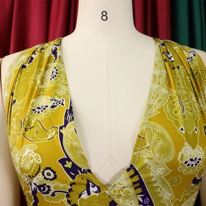 Detail of bohemian yellow floral print romper with deep V-neckline on a white mannequin