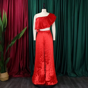 Detail of red pleated two-piece set featuring off-shoulder ruffle top and wide-leg trousers