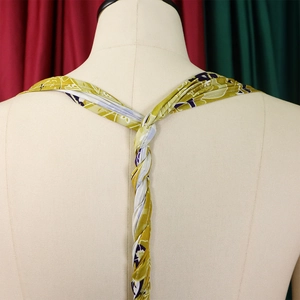 Detail of cross-back braided straps on printed halter jumpsuit in olive and purple
