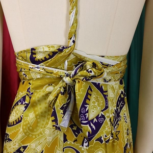 Detail of bohemian print halter jumpsuit with tie-back bow on yellow floral fabric