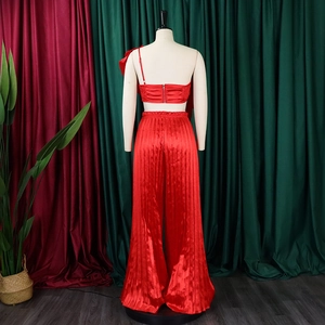 Detail of red off-shoulder satin top with back zipper and high-waist pleated wide-leg pants