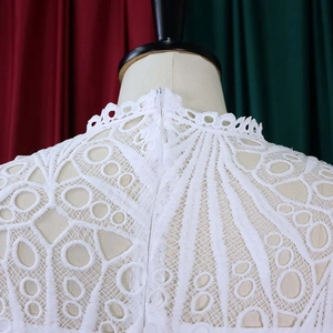 Detail of white hollow floral lace top featuring a stand collar and back invisible zipper