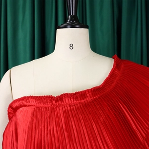 Detail of red accordion pleats and asymmetric neckline on a stylish two-piece set