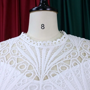 Detailed view of the white lace crochet neckline and intricate hollow design on the dress