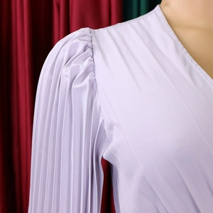Détail d'une robe plissée lavande avec manches bouffantes froncées et décolleté en V