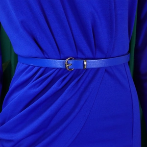 Close-up of a blue faux leather belt with a round gold buckle on a pleated mesh dress
