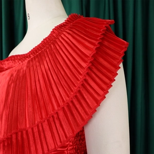 Detail of red pleated ruffles on satin one-shoulder top with glossy smooth texture