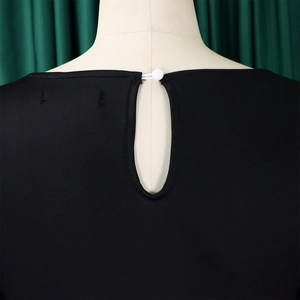 Detail view of the back neckline with teardrop cutout and button on a black dress