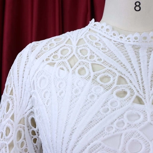 Detail of white lace dress showing standing collar and intricate floral hollow embroidery
