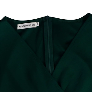 Detail of V-neckline featuring a hidden back zipper and brand tag on a dark green dress