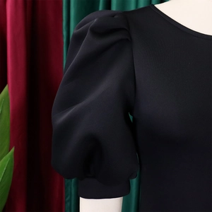 Close-up of black puff sleeve detail on a round neck dress with elegant pleats