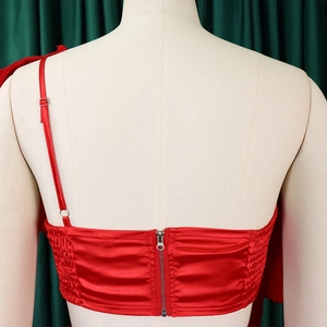 Detail of red satin one-shoulder top showing the metal zipper closure and fabric texture