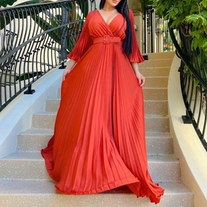 Détail d'une robe longue plissée rouge avec col en V profond et ceinture assortie