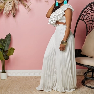 Detail of white two-piece set featuring ruffled one-shoulder top and pleated wide-leg pants