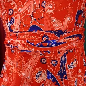 Detailed close-up of bohemian paisley print and pleated waistline on the red dress