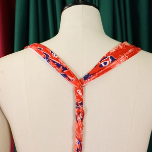 Detail of red floral print halter tie with woven texture on mannequin back