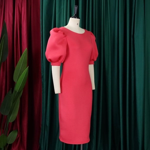 Detail of a coral pink puff sleeve midi dress with round neck on a mannequin display