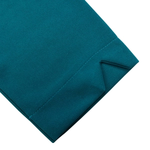Detail des pfauenblauen Kleides mit plissierter Kreppstruktur und V-förmigem Saumdesign