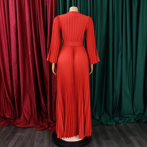 Détail d'une robe maxi plissée rouge avec manches accordéon et une ceinture assortie