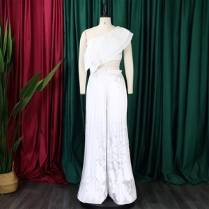 Detail of white pleated fabric texture on a one-shoulder top and wide-leg trousers set