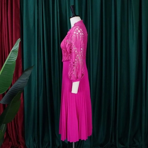 Detail of rose red dress with lace long sleeves and fine pleated skirt on mannequin