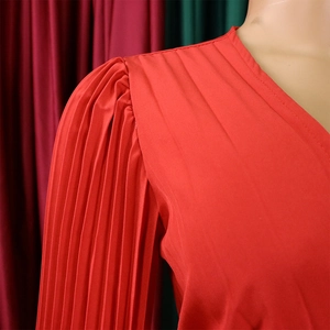 Gros plan du décolleté en V plongeant et des détails plissés de la robe de soirée en satin