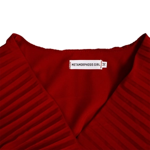 Détail d'une robe plissée rouge avec col en V, étiquette de taille et texture de tissu fine