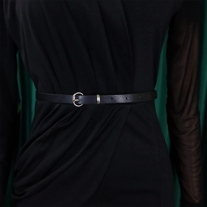 Close-up of thin black leather belt with silver circular buckle on a black dress