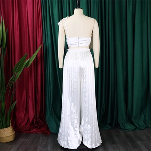 Detail of white satin two-piece set featuring pleated wide-leg pants and back zipper