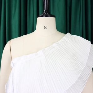 Detail view of white pleated one-shoulder top showing crisp accordion folds and fabric texture